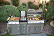 Outdoor kitchen with two grills, single side burner, and ingredients on a patio.