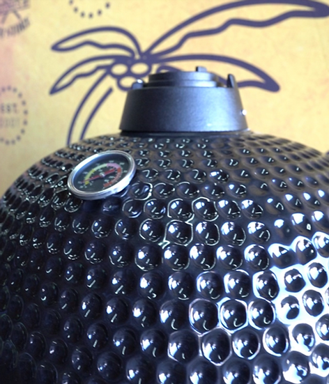 Black textured ceramic kamadogrill with thermometer on a yellow background