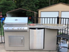Outdoor kitchen setup with grill and refrigerator on a patio