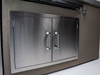 Stainless steel double door grill embedded in a stone wall