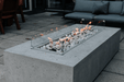 Concrete fire pit table with flames on a patio