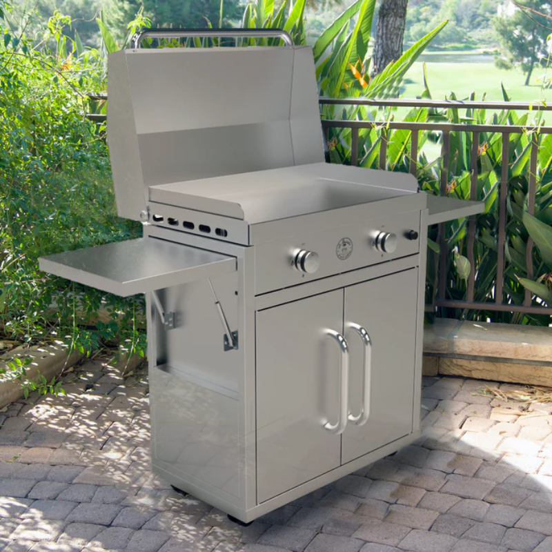 Stainless steel grill on a patio with greenery in the background