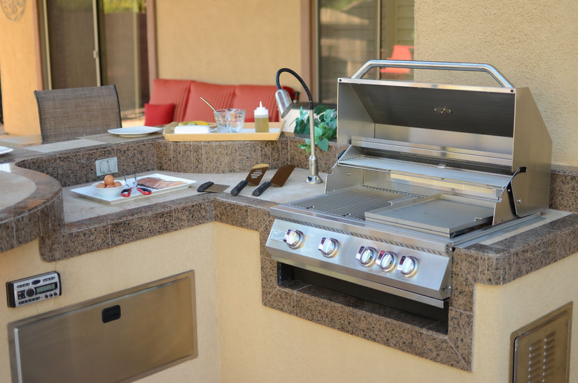 Outdoor kitchen with a large stainless steel grill with griddle plate and countertop.