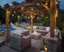 Outdoor patio with wooden pergola, seating area, and fire pit at dusk.