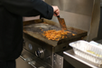 Person cooking food on a griddle with a spatula