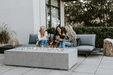 Three women sitting around a fire pit on a patio