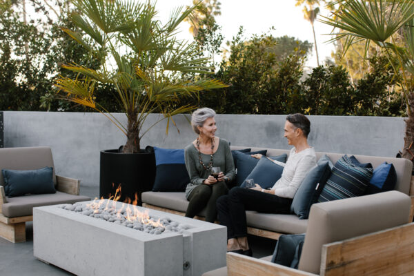 Two people sitting on a patio with a fire pit and outdoor furniture.